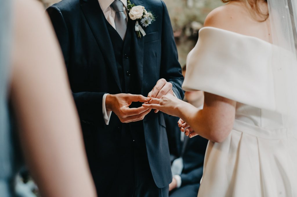 Couple exchange rings during ceremony in rustic barn.