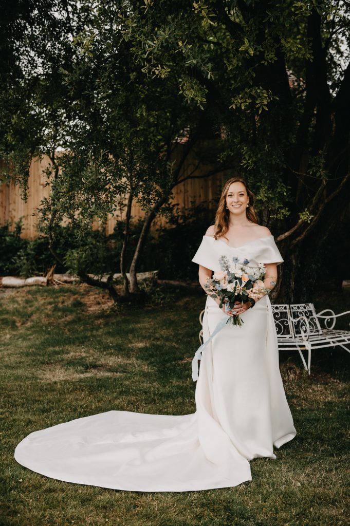 Elegant Bridal Portrait. Sarah wears a dress with a detachable wedding train and holding gorgeous floral bouquet. 