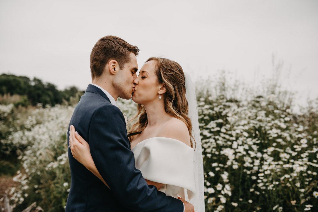 Couple embrace with a kiss, in a relaxed couples portrait photography session. 