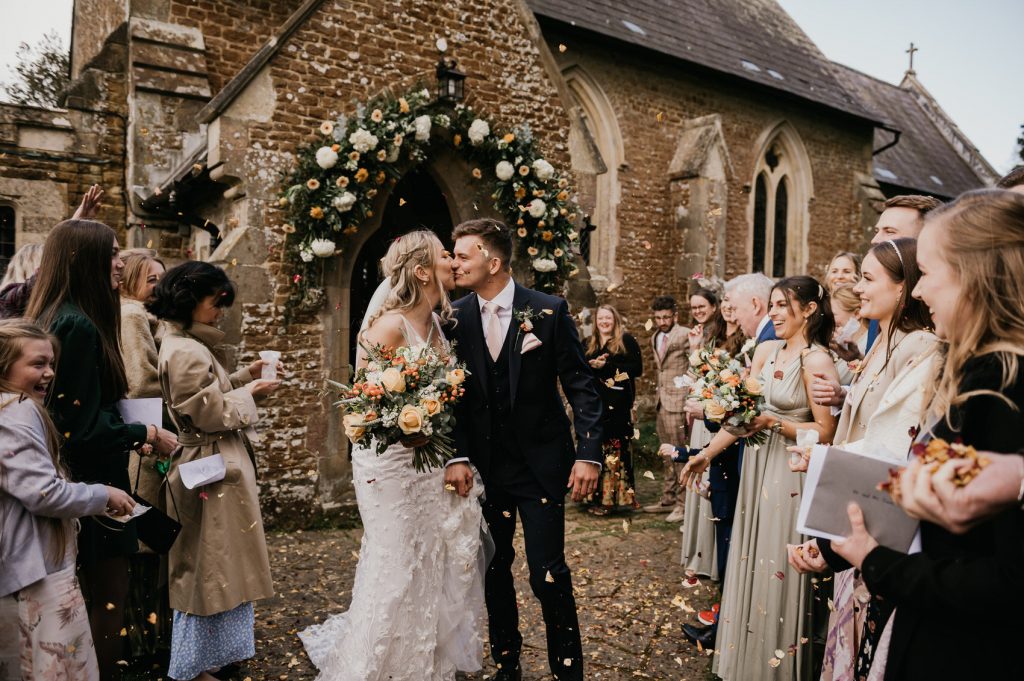 Couple Share Kiss During Confetti Aisle - Surrey Wedding Photographer