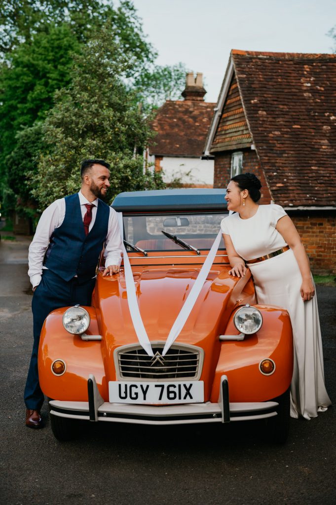 Couple Stand With Classic Wedding Car - Surrey Village Hall Wedding