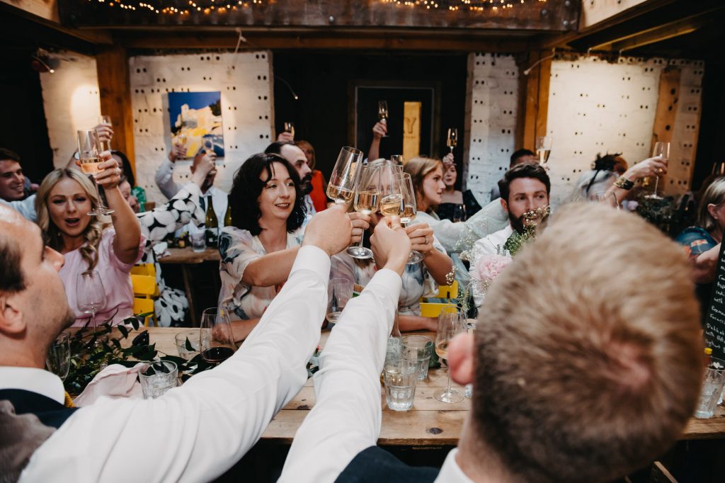 Guests Cheers Champagne Flutes During Speeches - Farnham Pottery Wedding