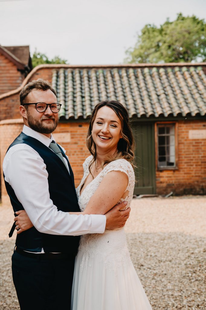 Couple Hug Tightly in Courtyard at The Farnham Pottery for Wedding Portraits