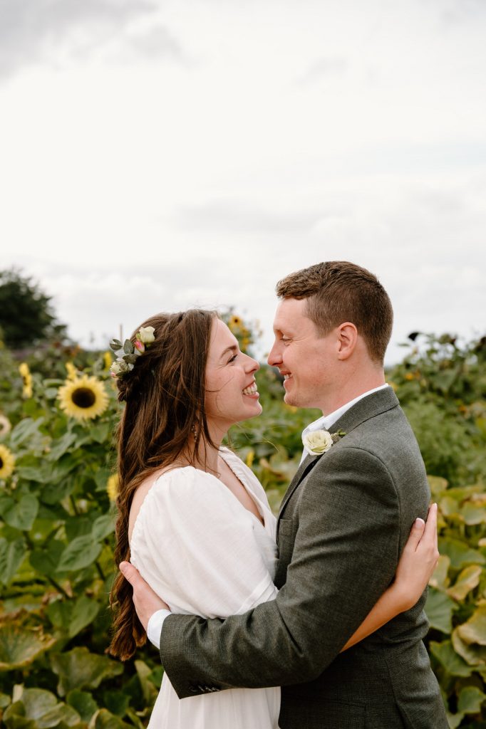 Couple Stand in Sunflower Field During Couples Portraits - RHS Wisley Garden Wedding