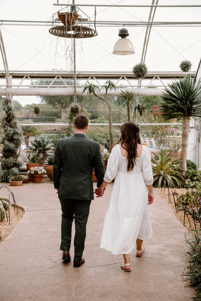 Couple Walk together in RHS Wisley Glasshouse - Natural Wedding Photography