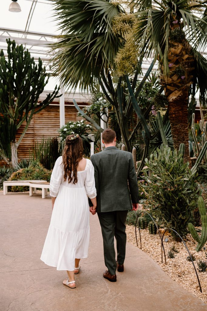 Couple Walk together in RHS Wisley Glasshouse - Natural Wedding Photography