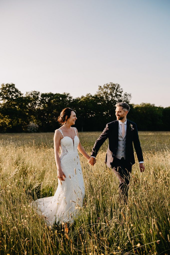 Couple Walk Through Field At Sunset - Surrey Barn Wedding