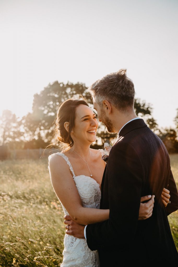 Couple Embrace in Field At Sunset - Surrey Barn Wedding