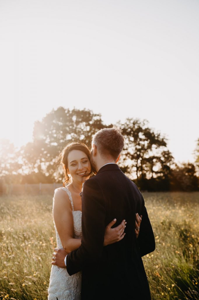 Couple Embrace in Field At Sunset - Romantic Surrey Barn Wedding