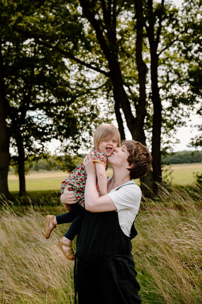Mother and daughter share a kiss and a cuddle. 