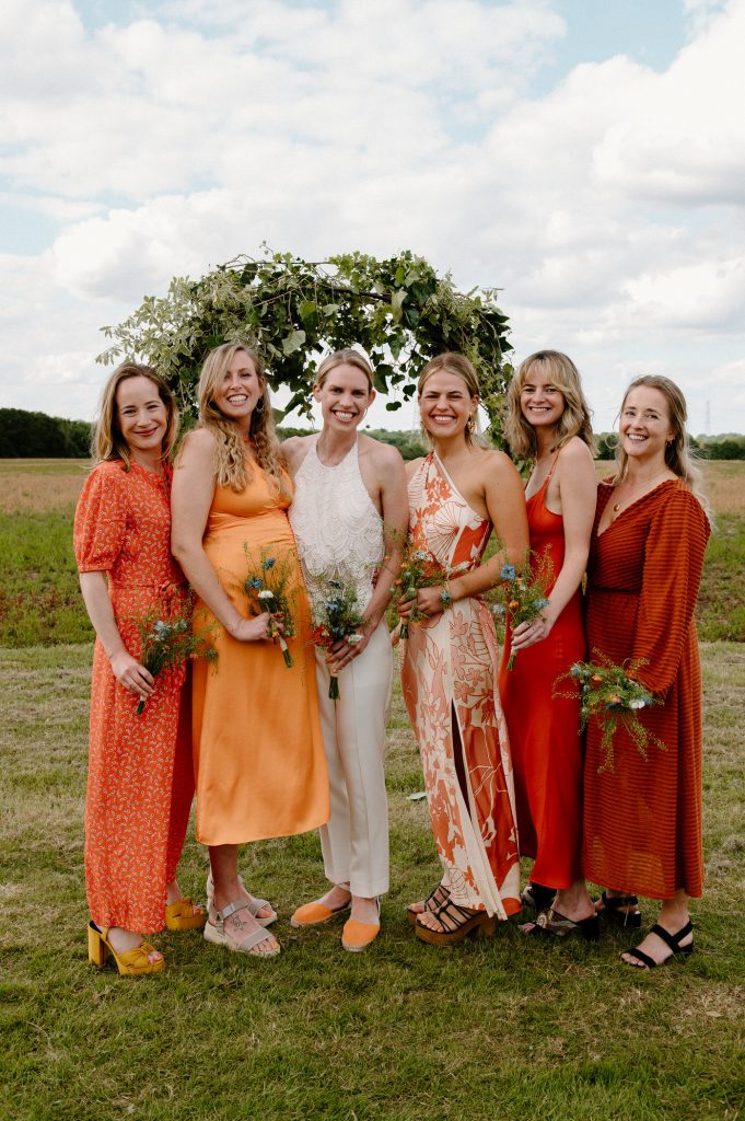 Bridal Party all Dressed in Miss Matching Outfits in Different Shades of Orange